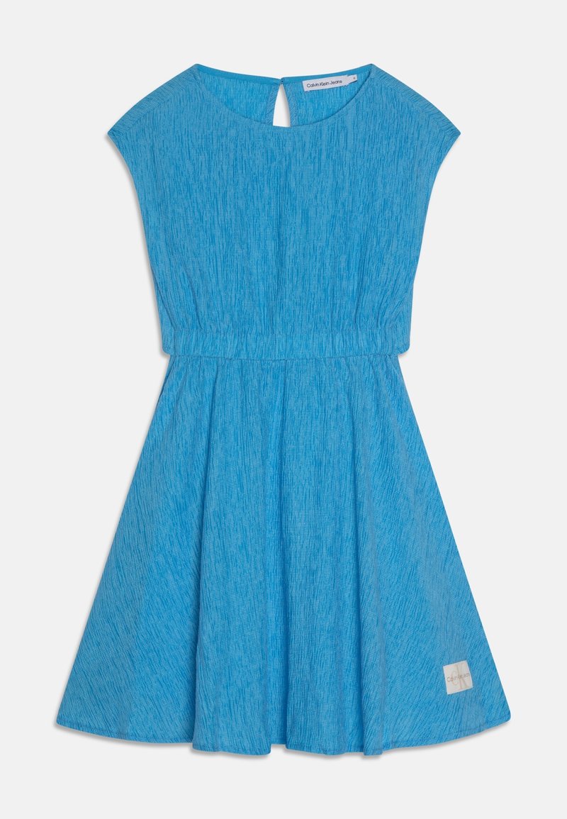 Robe courte à manches courtes texturée bleue avec taille cintrée, encolure ronde, petite ouverture en clé à l'arrière, et étiquette Calvin Klein Jeans sur l'ourlet de la jupe.