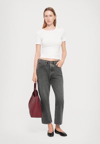 Top bianco a maniche corte, jeans in denim grigi elegantissimi a vita alta, ballerine nere e borsa a tracolla bordeaux; tessuti morbidi e vestibilità rilassata.