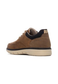 Zapatilla de cuero marrón con punta redondeada, cuello texturizado negro, suela beige y ojales de metal para los cordones.