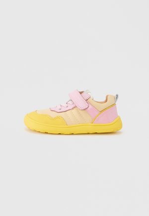 Zapatilla infantil en rosa y amarillo con una correa de velcro, material texturizado, puntera redondeada y suela de goma para tracción.