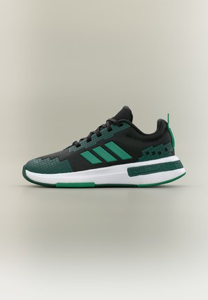 Baskets de sport noires et vertes avec un design pixellisé, trois bandes sur le côté, semelle blanche et accents verts sur la semelle extérieure et la languette du talon.