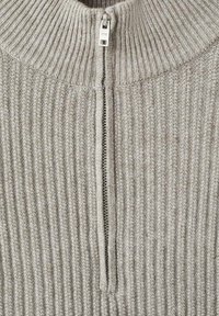 Maglione grigio a coste con colletto alto e zip frontale. Presenta una texture morbida e un motivo sottile su tutta la stoffa.
