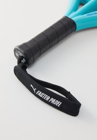 Manico di racchetta da padel blu con impugnatura in gomma nera, dotato di una cinghia nera contrassegnata "FASTER PADEL". Superficie liscia e design ergonomico.