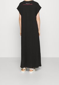 Černé maxi šaty z měkké tkaniny, s krátkými rukávy a nápisem na zádech "REPLAY TO JE PŘÍBĚH LÁSKY." Nosit s bílými teniskami.