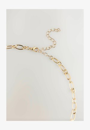 Gold chain necklace with oval links and a lobster clasp, featuring an adjustable extension chain on a light neutral background.