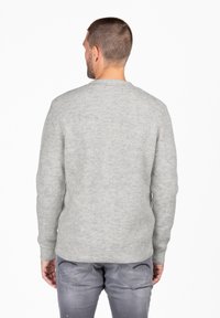 Grijze geribbelde trui met een ronde hals en lange mouwen. Zachte textuur, aansluitende pasvorm en een subtiel patroon zijn zichtbaar.