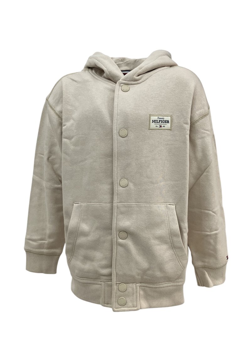 Giacca con cappuccio beige realizzata in tessuto misto cotone, dotata di chiusura con bottoni frontali, due tasche laterali e cappuccio. Patch con logo Tommy Hilfiger.