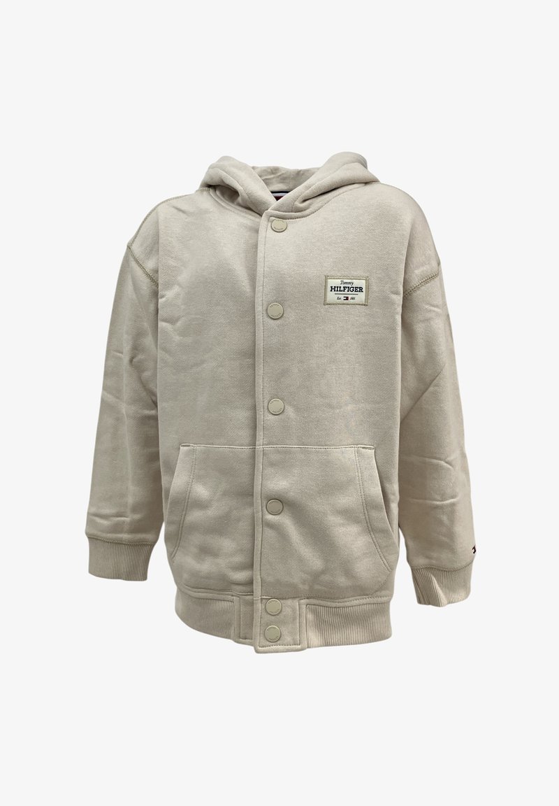 Giacca con cappuccio beige realizzata in tessuto misto cotone, dotata di chiusura con bottoni frontali, due tasche laterali e cappuccio. Patch con logo Tommy Hilfiger.