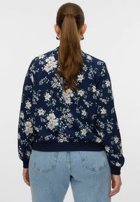 Navy bomber jacket featuring a white floral pattern, ribbed cuffs and hem, with a relaxed fit and lightweight fabric for comfort.