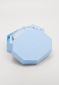 Lichtblauwe octagonale doos van textuurmateriaal, met een geperst logo op de bovenkant en een zilveren rits voor sluiting.