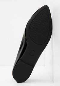 Semelle d'une chaussure plate pointue en cuir verni noir avec une semelle texturée et un motif de logo MK pour une meilleure adhérence.