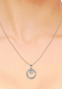 Collana con pendente circolare in argento, dotata di un centro in cristallo e pietre trasparenti lungo il bordo esterno, sospesa a una delicata catena.