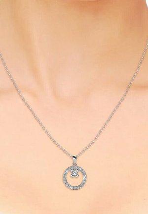 Collana con pendente circolare in argento, dotata di un centro in cristallo e pietre trasparenti lungo il bordo esterno, sospesa a una delicata catena.