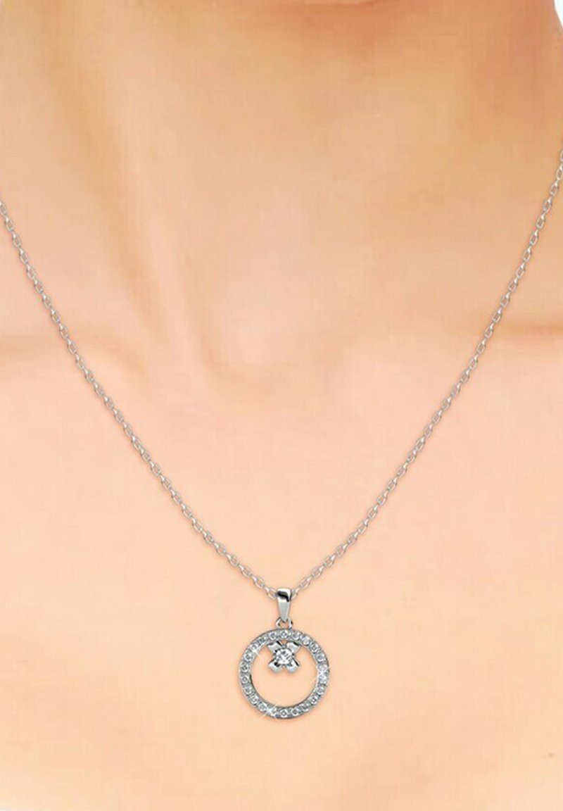 Collana con pendente circolare in argento, dotata di un centro in cristallo e pietre trasparenti lungo il bordo esterno, sospesa a una delicata catena.