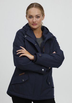 Veste imperméable bleu marine avec capuche, fermeture éclair à l'avant et fermeture à pression ; comprend deux poches latérales et des accents en cuir marron.