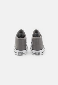 Grå hög häl sneaker med en strukturerad läderfinish, svart och vit detaljer och klassisk Converse-märkning vid hälkappan.