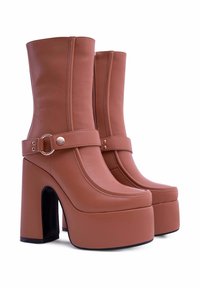 Stivaletti alla caviglia in finta pelle marrone con platform, alta zeppa quadrata, zip laterale, una cinturino con un accento metallico circolare e dettagli cuciti.