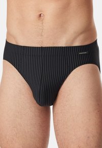 Slip neri a righe con sottili linee bianche verticali. Presenta un design a vita bassa e una consistenza morbida e liscia. Etichetta del logo cucita sull'elastico in vita.