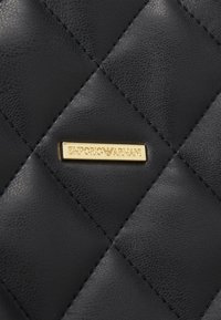 Svart vadderad läder med en guldplatta med Emporio Armani-logotyp. Texturerad yta med diamantformad mönstring och sydda detaljer.