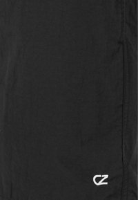 Sorte shorts lavet af letvægtsstof, med et struktureret design og et hvidt broderet logo nederst til højre.