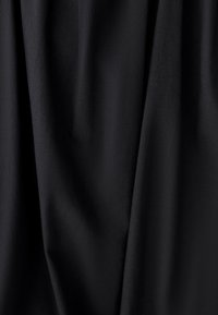 Zwarte stoffen gordijnen met een gladde textuur, voorzien van subtiele kreukels en plooien, wat wijst op een lichtgewicht, vloeiend ontwerp.