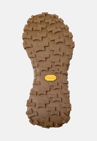 Vibram podrážka, hnědá guma s texturovaným vzorem a hlubokými výstupky pro trakci. Obsahuje žlutou nálepku Vibram se velikostí 38.