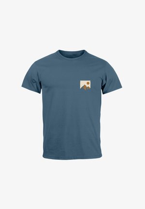 Blaues Baumwoll-T-Shirt mit kurzen Ärmeln, das ein kleines hellfarbiges Grafikdesign in Form einer Tasche mit einem Berg- und Sonnenmotiv zeigt.