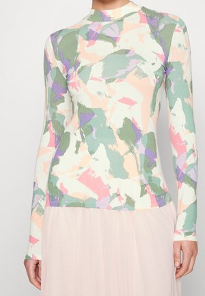 Top met lange mouwen en col in een abstract pastelkleurig patroon van groen, roze, paars en crème, gedragen bij een lichtroze rok.