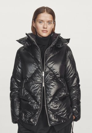 Black padded jacket made from shiny nylon material. Features a high collar, zipper front, and diamond quilted pattern with side pockets.