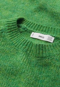Grüner Strickpullover mit geripptem Ausschnitt. Weiche Textur, gemischte Grüntöne. Anhänger mit der Marke "MNG" sichtbar.