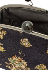 Czarna torba z materiału z kwiatowym wzorem, metalową ramą i zapięciem na zamek. Wnętrze zawiera kieszeń na zamek błyskawiczny. Teksturowana zewnętrzna strona z szczegółowym wzorem.