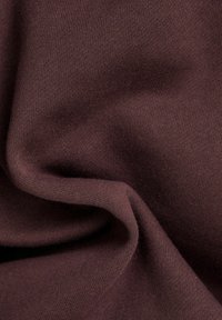 Brązowa elastyczna tkanina o gładkiej teksturze z subtelnym prążkowaniem, ułożona w delikatne fałdy. Idealna do zastosowań odzieżowych.