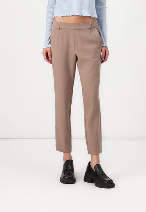 Beige kalhoty na míru s hladkou strukturou, slim fit a předními záhyby, doplněné černými robustními mokasíny a světle modrým pleteným topem.