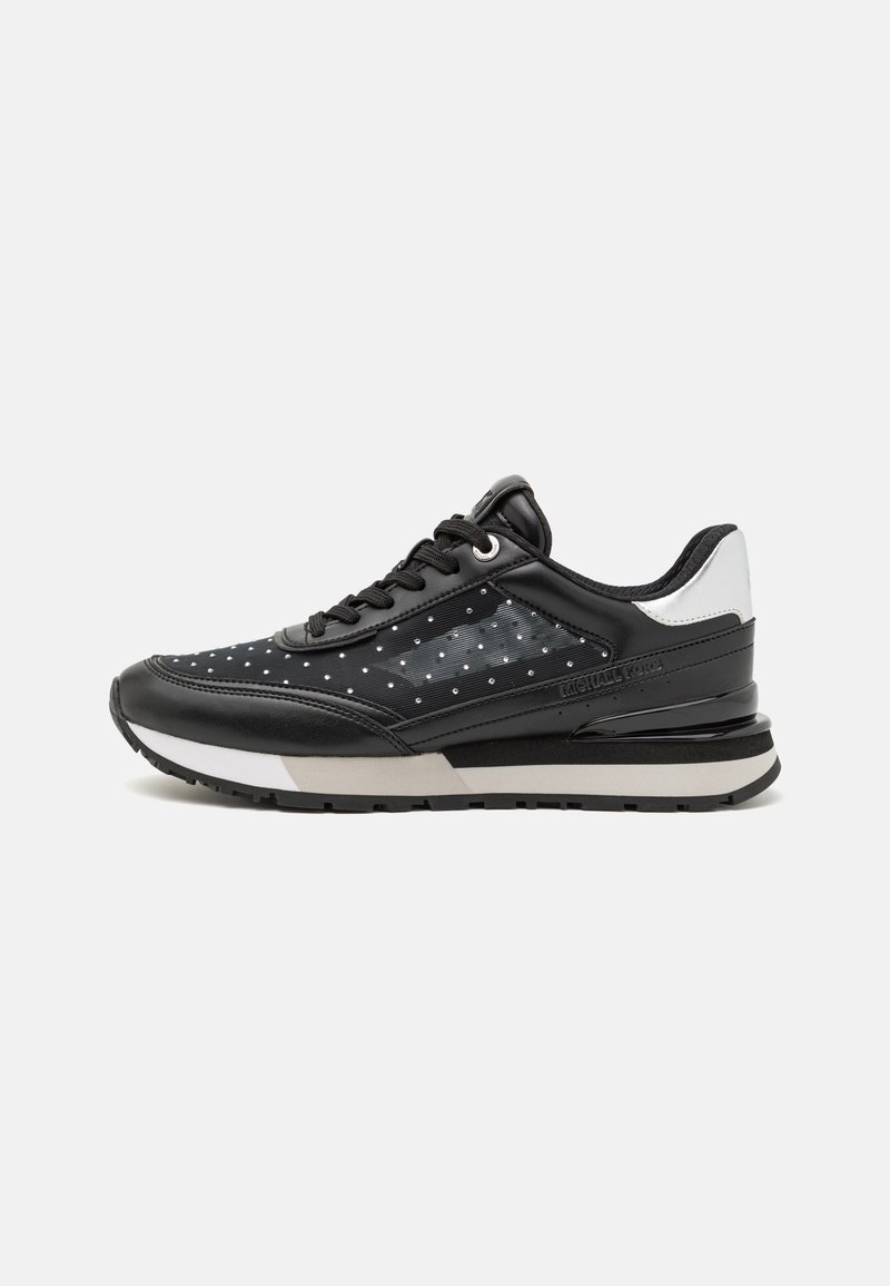 Schwarze Sneaker mit glänzendem synthetischem Leder und Mesh-Obermaterial, gepunktetem Muster, gepolsterter Schuhkragen und einer weißen sowie grauen Zwischensohle.