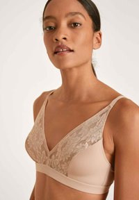 Kanten en stoffen bralette in nude met een v-hals ontwerp, voorzien van een bloemenkant bovenlaag en een gladde band. Dunne verstelbare bandjes.