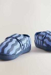 Blå tygskor med ett vågigt mönster i varierande blå nyanser, med kardborreband och en hållbar gummisula.