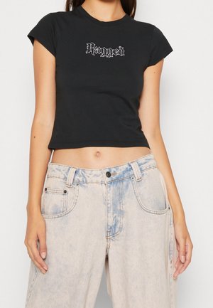 T-shirt noir raccourci avec le texte blanc "Ragged", associé à un jean large en délavé bleu clair. Matériau en coton confortable.
