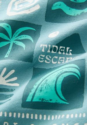 Trykt stof med en turkis baggrund, hvide palmer, bølger og teksten "TIDAL ESCAPE" i fede sorte bogstaver.