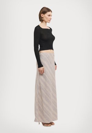 Black ribbed long-sleeve top paired with a beige skirt featuring diagonal stripes and a soft texture, complemented by open-toe heeled sandals.