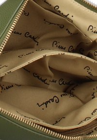 Vista interna di una borsa verde con zip, foderata in tessuto beige stampato ripetutamente con il logo "Pierre Cardin" in nero.