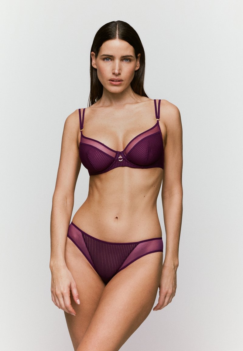 Conjunto de lencería a rayas moradas que incluye un sujetador estructurado con aros y unas braguitas de bikini transparentes a juego, ambos con tirantes ajustables.