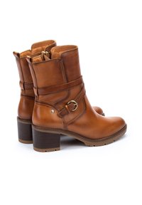 Bottes de cheville en cuir marron avec une fermeture éclair sur le côté, des détails de sangle à boucle et un talon empilé. Fini lisse avec un design à bout rond.