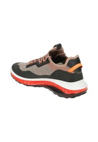 Chaussures de sport avec une tige en mesh respirant beige et noire, ornées d'accents orange, d'une semelle intermédiaire blanche et d'une semelle en caoutchouc.
