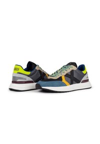 Zapatillas con una mezcla de materiales que incluye malla, ante y cuero. Los colores incluyen gris, azul, amarillo y acentos verdes. Marca visible.