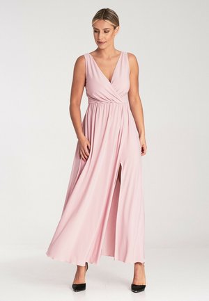 Rosa Maxikleid aus weichem Stoff mit tiefem V-Ausschnitt, geraffter Taille und vorderem Schlitz. Kombiniert mit schwarzen High Heels, glatter Textur und fließendem Design.