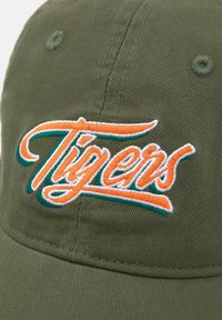 Cappello verde oliva con testo ricamato "Tigers" in arancione e teal. Presenta un tessuto testurizzato e un accento cucito sulla visiera.