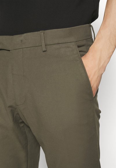 Olive green chinos made of a smooth fabric, featuring side pockets and a flat front design. Belt loops and a tailored fit are present.