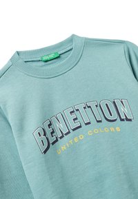 Felpa azzurra Benetton con colletto a costine e la scritta "BENETTON UNITED COLORS" stampata sul petto in caratteri corsivi.