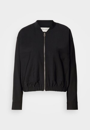 Čierna bomber bunda so zipsovým zapínaním, dvoma prednými vreckami a zhromaždeným lemom. Má dlhé rukávy a ľahký materiál.