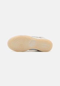 Schoenzool met cirkelvormige en lineaire profielpatronen in doorschijnend beige rubber op een witte achtergrond.